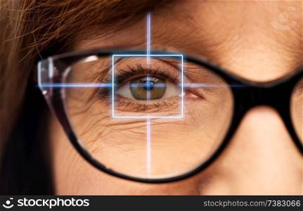 vision, eye surgery and ophthalmology concept - close up of face of senior woman in glasses with laser light. close up of senior woman eye with laser light