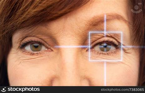 vision, eye surgery and security concept - eyes of senior woman with laser light. close up of senior woman eyes with laser light