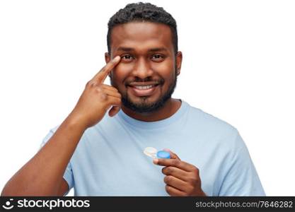 vision, eyesight, ophthalmology and people concept - smiling young african american man applying contact lenses over white background. young african american man applying contact lenses
