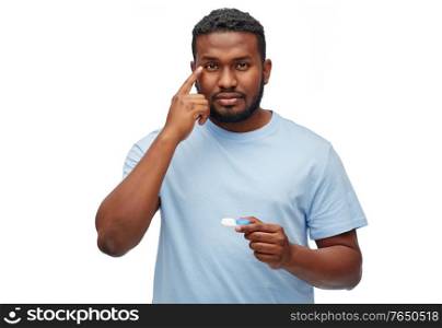 vision, eyesight, ophthalmology and people concept - young african american man applying contact lenses over white background. young african american man applying contact lenses