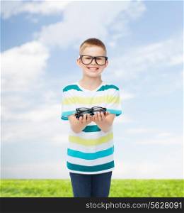vision, health, childhood and people concept - smiling little boy in eyeglasses holding spectacles natural background