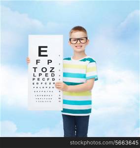 vision, ophthalmology, childhood and people concept - smiling little boy in eyeglasses with with eye chart over cloudy sky background