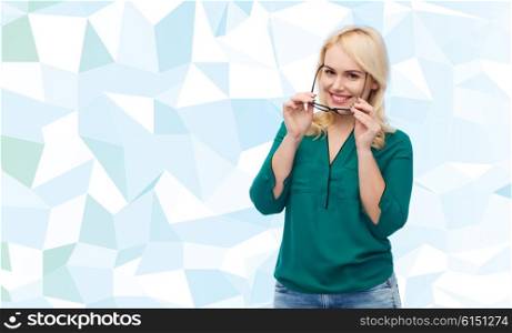 vision, optics, education and people concept - smiling young woman with eyeglasses over blue background