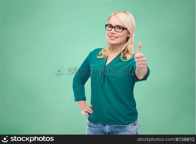 vision, optics, education, gesture and people concept - smiling young woman with eyeglasses showing thumbs up over green school chalk board background
