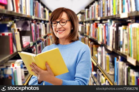 vision, wisdom and old people concept - portrait of smiling senior woman in glasses reading book over grey background. portrait of senior woman in glasses reading book