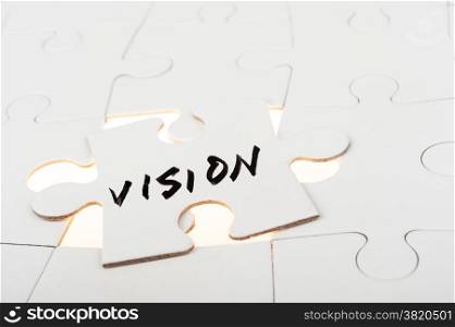 Vision word written on a piece of puzzle over group of paper jigsaw puzzles