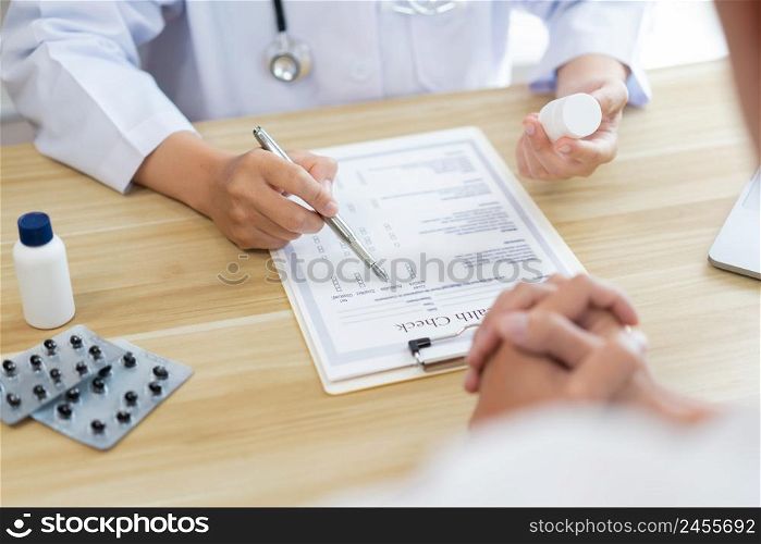 Visiting a doctor concept A patient being suggested by the doctor to take a pill in the white bottle for treatment
