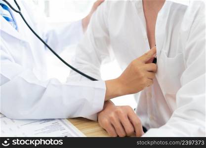 Visiting a doctor concept A patient sitting still and being examined on his chest by a doctor