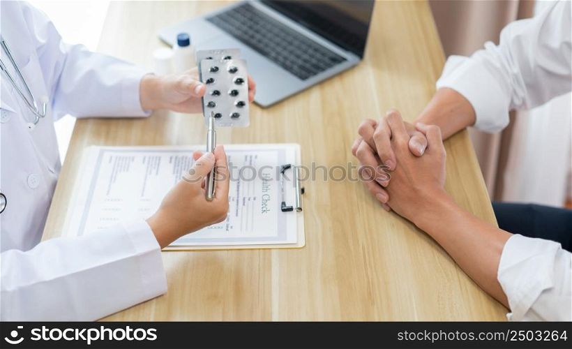 Visiting a doctor concept A physician suggesting his patient to take capsule for treatment and explaining how to take them