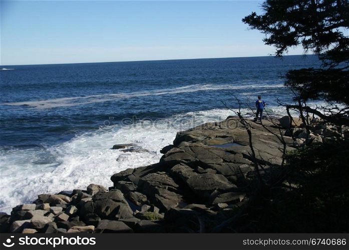 Visitor watching the tide from rocky perch, Schoodic Point, Acadia National park, Maine, New England