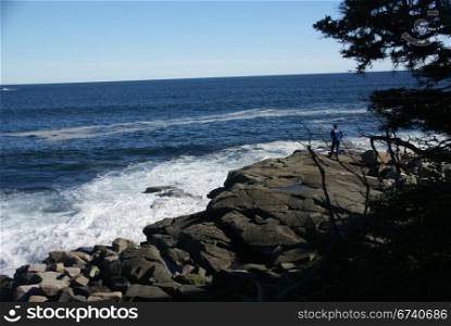 Visitor watching the tide from rocky perch, Schoodic Point, Acadia National park, Maine, New England