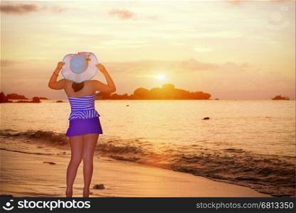 Visitors woman in a blue swimwear and hat standing looking the beautiful landscape of sky over the sea happily on the beach during sunrise at Koh Miang Islands, Mu Ko Similan National Park, Phang Nga, Thailand