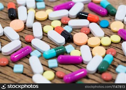 vitamin and Many type of medical drugs pills capsules and medicine poring from the bottle with wooden background. Used for manufacturing health industry concept.