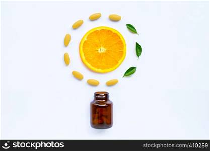 Vitamin C bottle and pills with orange fruit on white background