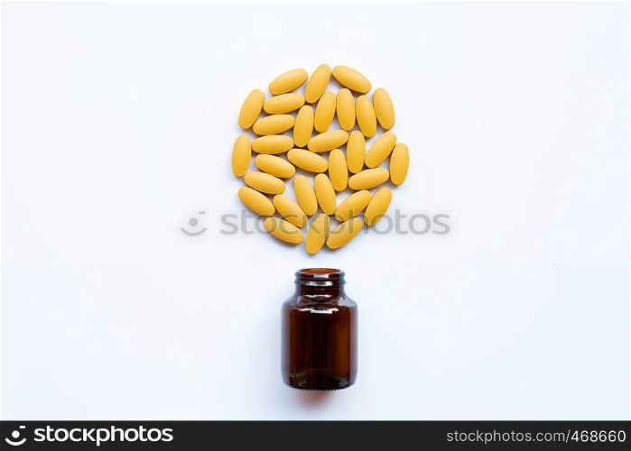 Vitamin C bottle and pills with orange fruit on white background