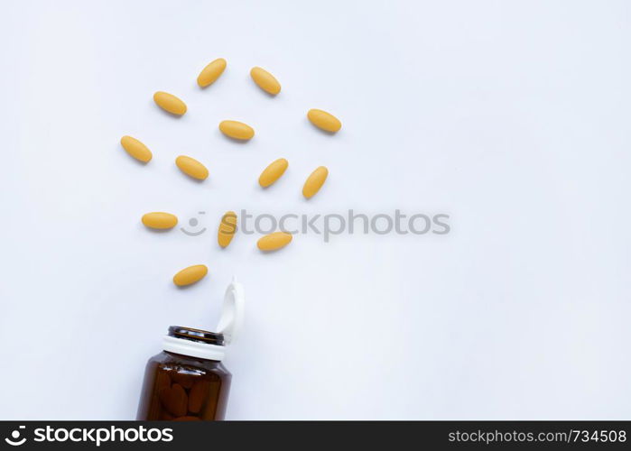 Vitamin C bottle and pills with orange fruit on white background. Copy space