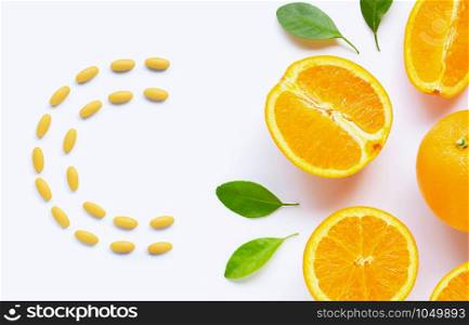 Vitamin C pills with fresh orange citrus fruit isolated on white background.