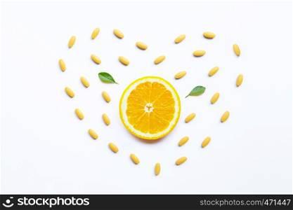 Vitamin C pills with orange fruit on white background