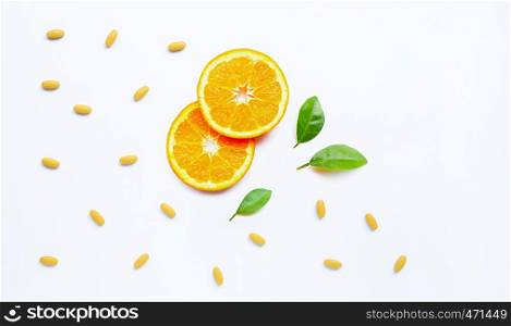 Vitamin C pills with orange fruit on white background