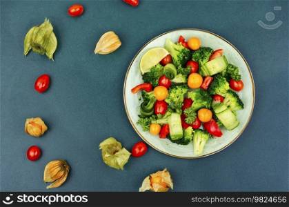 Vitamin salad with broccoli, tomato, cucumber and physalis. Healthy food concept, space for text. Spring vegetable salad decorated with physalis.