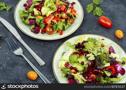 Vitamin salad with greens, pepper, red lettuce and cucumber, decorated with pomegranate. Diet menu. Spring bright vegetable salad.