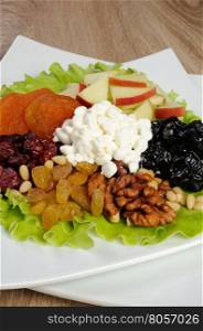 Vitamin salad with nuts, apples, dried fruit and cottage cheese in lettuce leaves