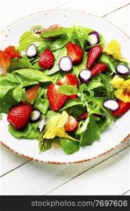 Vitamin salad with strawberries,spinach,nasturtium and arugula on white background. Colorful summer salad