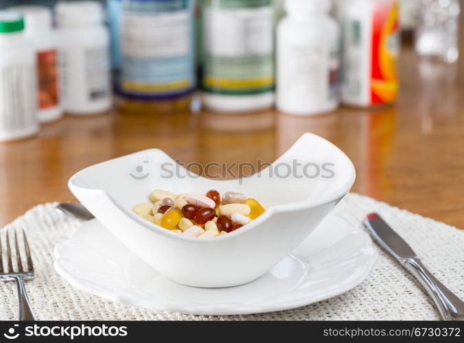 Vitamins in bowl of tablets for breakfast in kitchen with rows of bottles in background