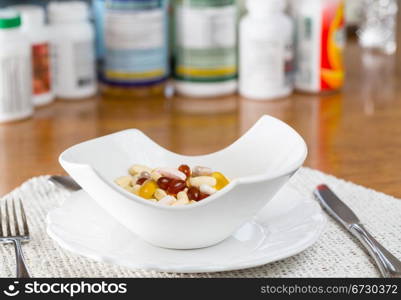 Vitamins in bowl of tablets for breakfast in kitchen with rows of bottles in background