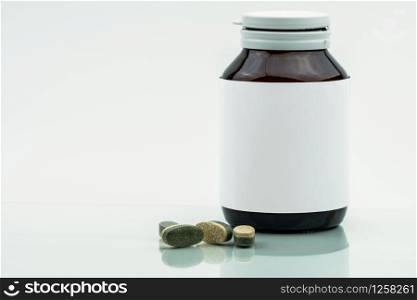 Vitamins, supplements and minerals dual layer tablets pills and medicine amber glass bottle with blank label isolated on white background with copy space. Use for vitamins and supplements advertising.