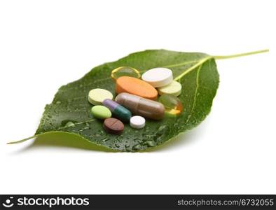 vitamins, tablets and pills on green leaf