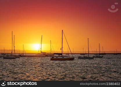 Vivid sunset at marina, silhouettes of yachts against orange sky, La Paz, Mexico