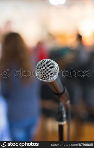 Vocal Microphone in focus against blurred audience at the conference or live concert