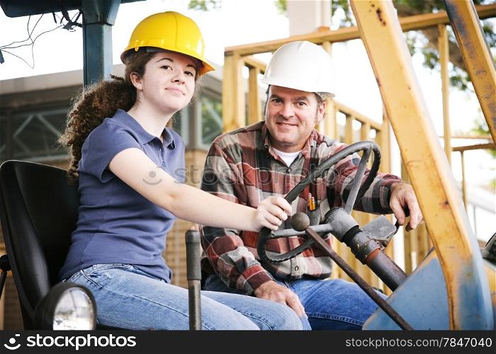 Vocational instructor teaching a young construction apprentice how to drive heavy equipment.