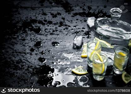 Vodka in glasses with lemon and ice. On the black chalkboard.. Vodka in glasses with lemon and ice.