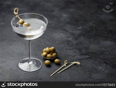 Vodka martini gin cocktail in modern glass with olives in metal bowl and bamboo sticks on black background.Top view