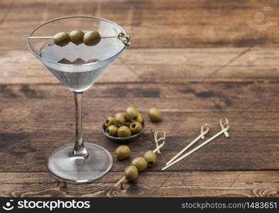 Vodka martini gin cocktail in original glass with olives in metal bowl and bamboo sticks on wooden background. Space for text