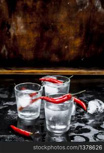 Vodka shots with chili pepper. On a wooden background.. Vodka shots with chili pepper.