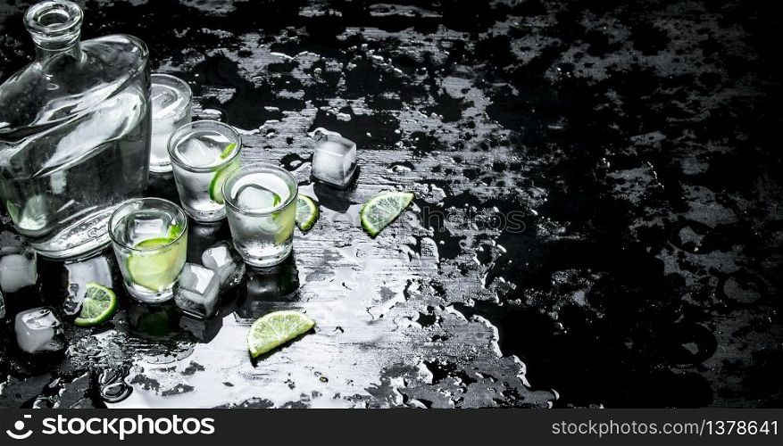 Vodka shots with lime and ice. On the black chalkboard.. Vodka shots with lime and ice.