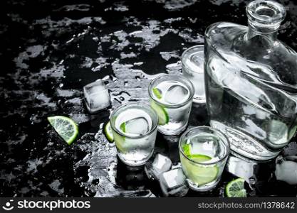 Vodka shots with lime and ice. On the black chalkboard.. Vodka shots with lime and ice.