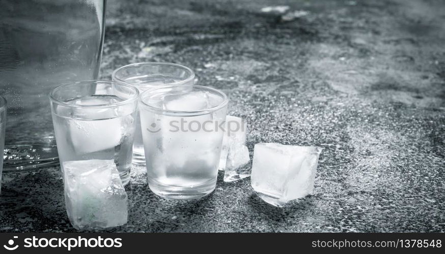 Vodka with ice in glasses. On a rustic background.. Vodka with ice in glasses.