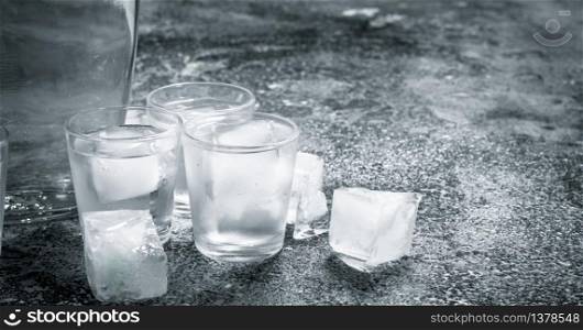 Vodka with ice in glasses. On a rustic background.. Vodka with ice in glasses.