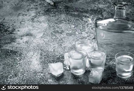 Vodka with ice in glasses. On a rustic background.. Vodka with ice in glasses.