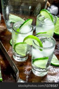 Vodka with lime and ice on a wooden tray. On a rustic background.. Vodka with lime and ice on a wooden tray.