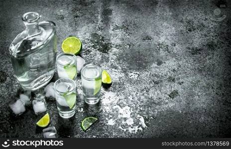 Vodka with pieces of lime and ice cubes. On a rustic background. Vodka with pieces of lime and ice cubes.