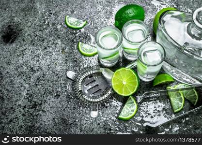 Vodka with pieces of lime and ice cubes. On a rustic background. Vodka with pieces of lime and ice cubes.