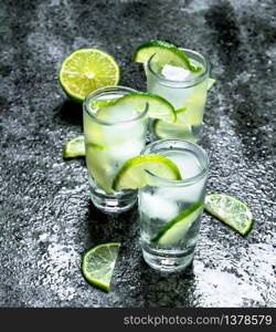 Vodka with pieces of lime and ice cubes. On a rustic background. Vodka with pieces of lime and ice cubes.