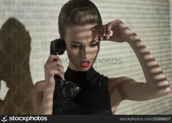 vogue creative portrait of sensual elegant woman talking with worried expression on phone in indoor half-light atmosphere