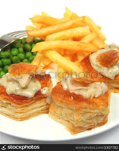 Vol-au-vents filled with turkey in a creamy herb sauce and served with potato chips and boiled peas.