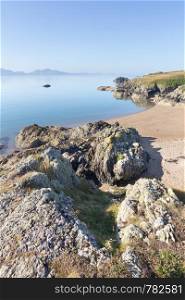 Volcanic rock and beach on Llanddwyn Island, Anglesey, Wales with the Llyn peninsula in the background